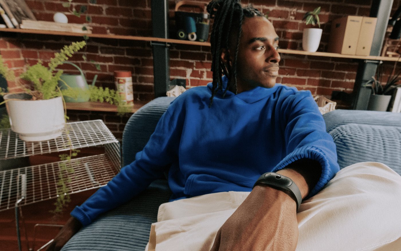 Man wearing Bee Frontier AI wristband on sofa